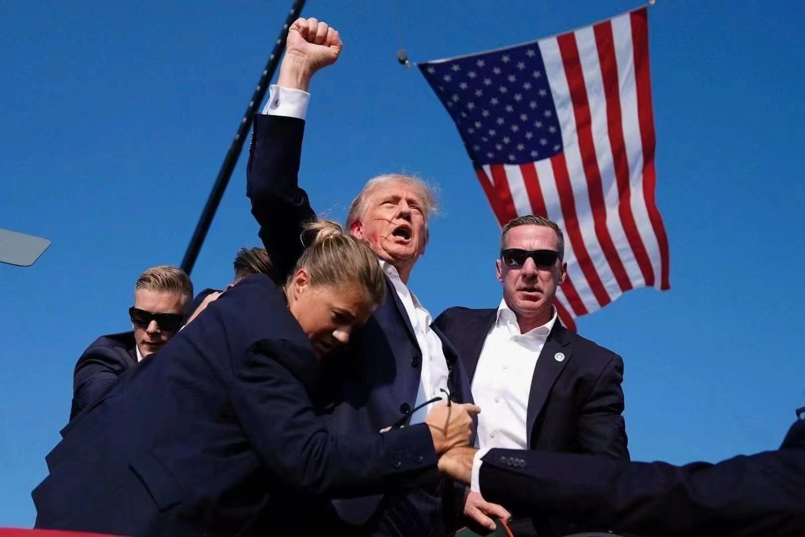Historical photograph of Donald Trump raising his fist beside security personnel
